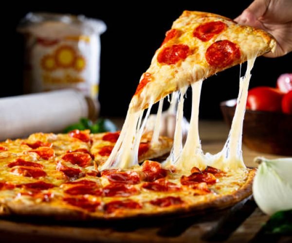 A person getting a piece of cheesy pepperoni pizza